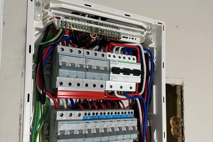 An electrician testing circuit breakers inside a switchboard