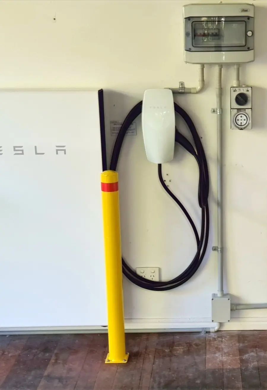 A white EV wall connector with its cable coiled on the wall