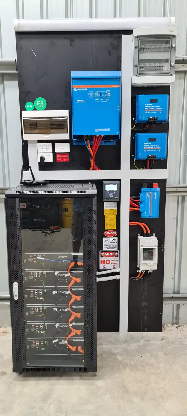 An off-grid power cabinet with Victron controllers and a rack of lithium batteries